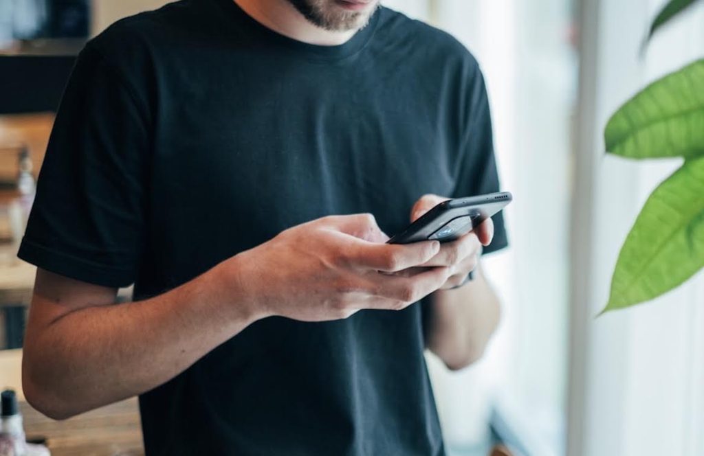 出張マッサージKIKUTOCOへスマホで予約を入れる男性顧客